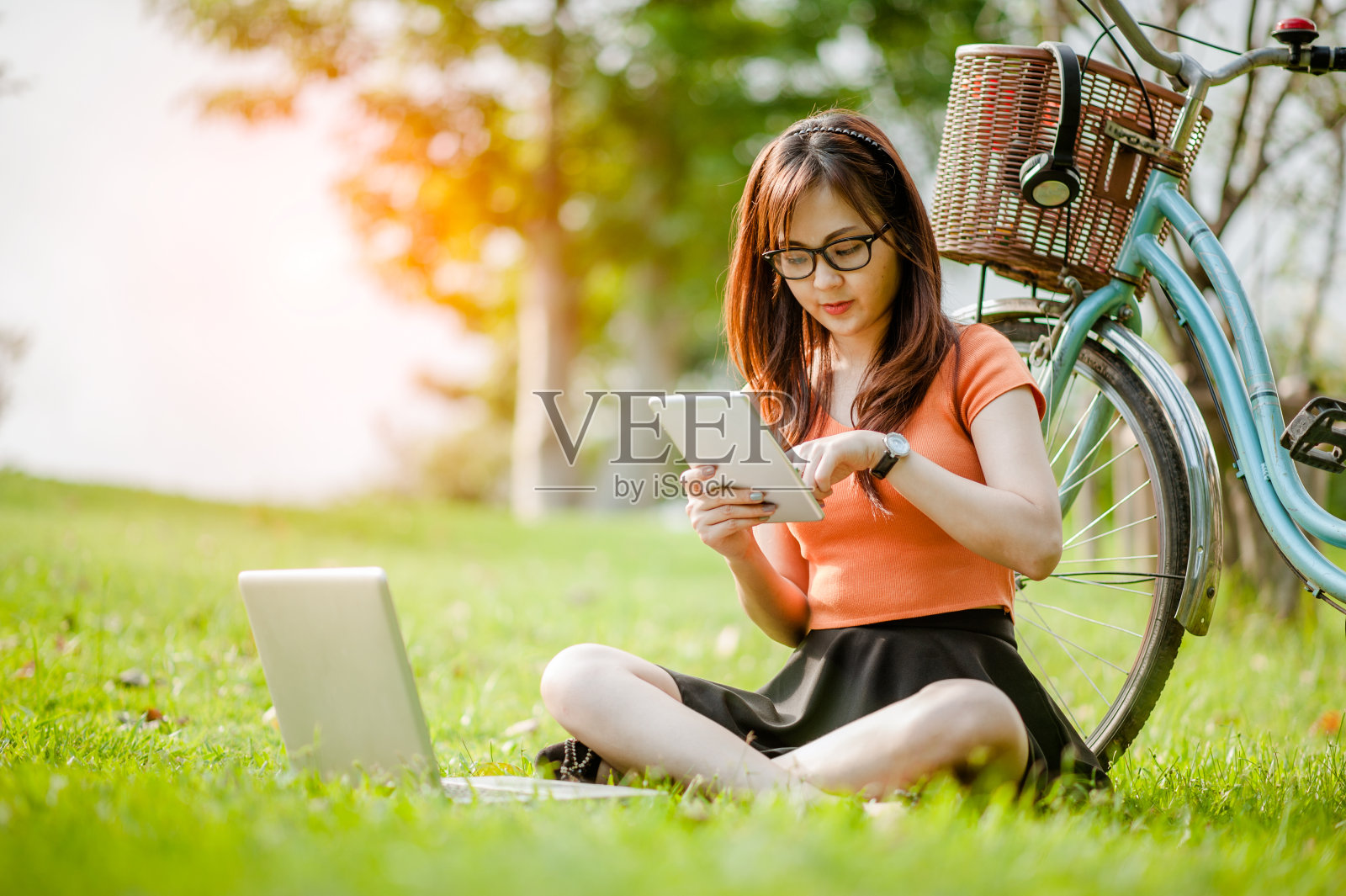 年轻美丽的亚洲女人工作与笔记本电脑/互联网/网上购物在户外公园。照片摄影图片