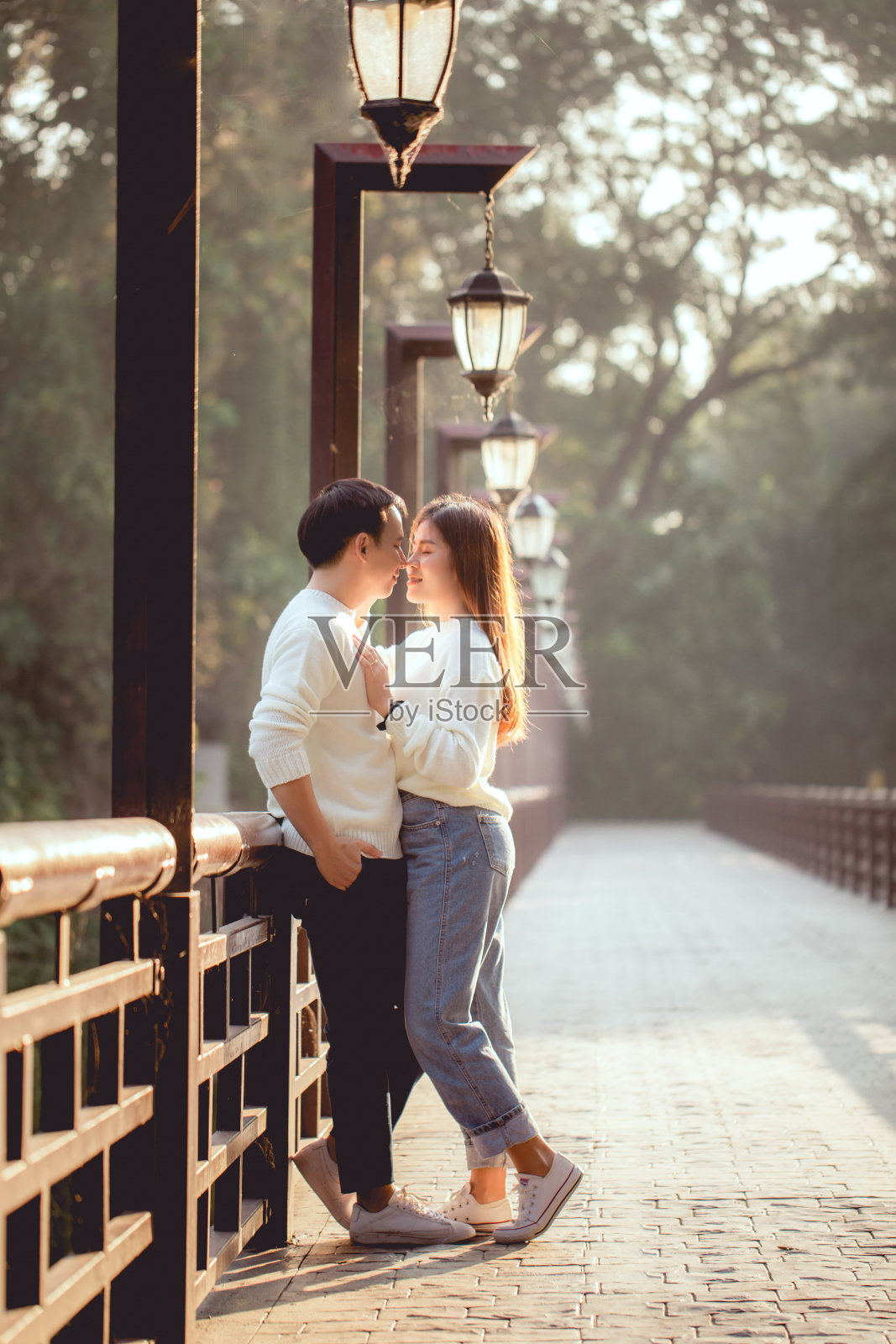 这对亚洲夫妇在桥上注视着，远处的背景是森林。照片摄影图片