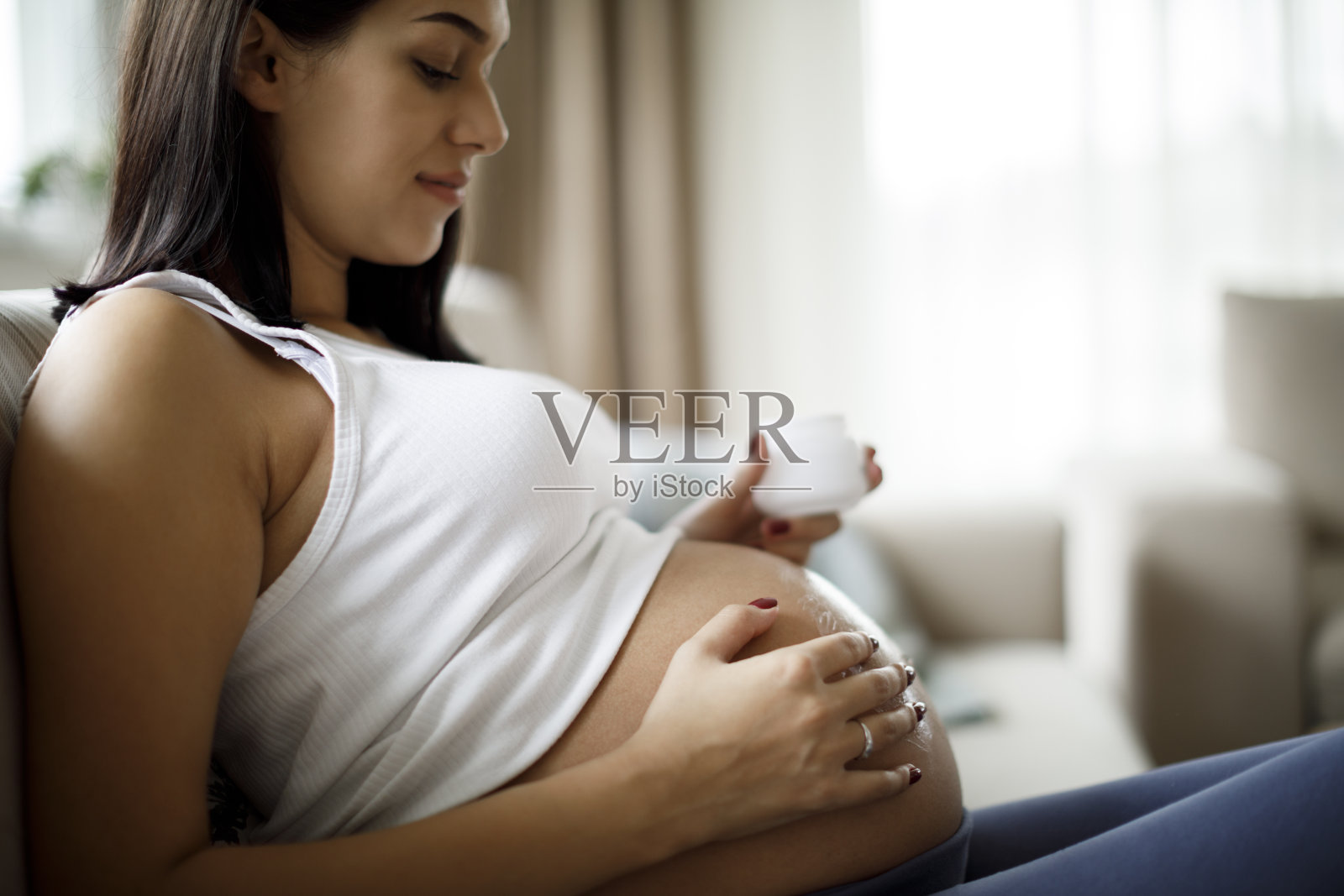 孕妇在腹部涂抹护肤霜以防止妊娠纹照片摄影图片