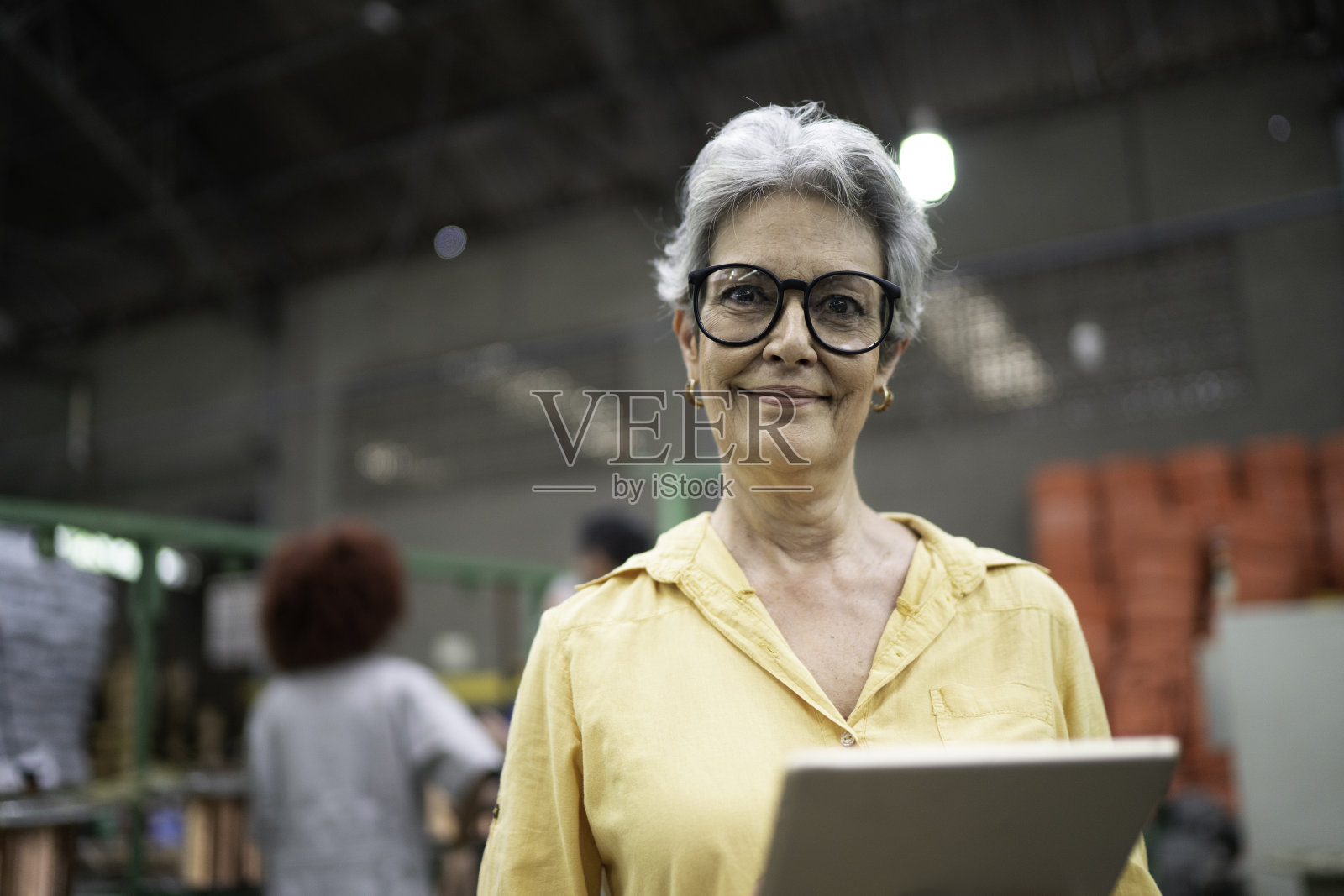 一位在工厂工作的高级女商人使用数字平板电脑的肖像照片摄影图片