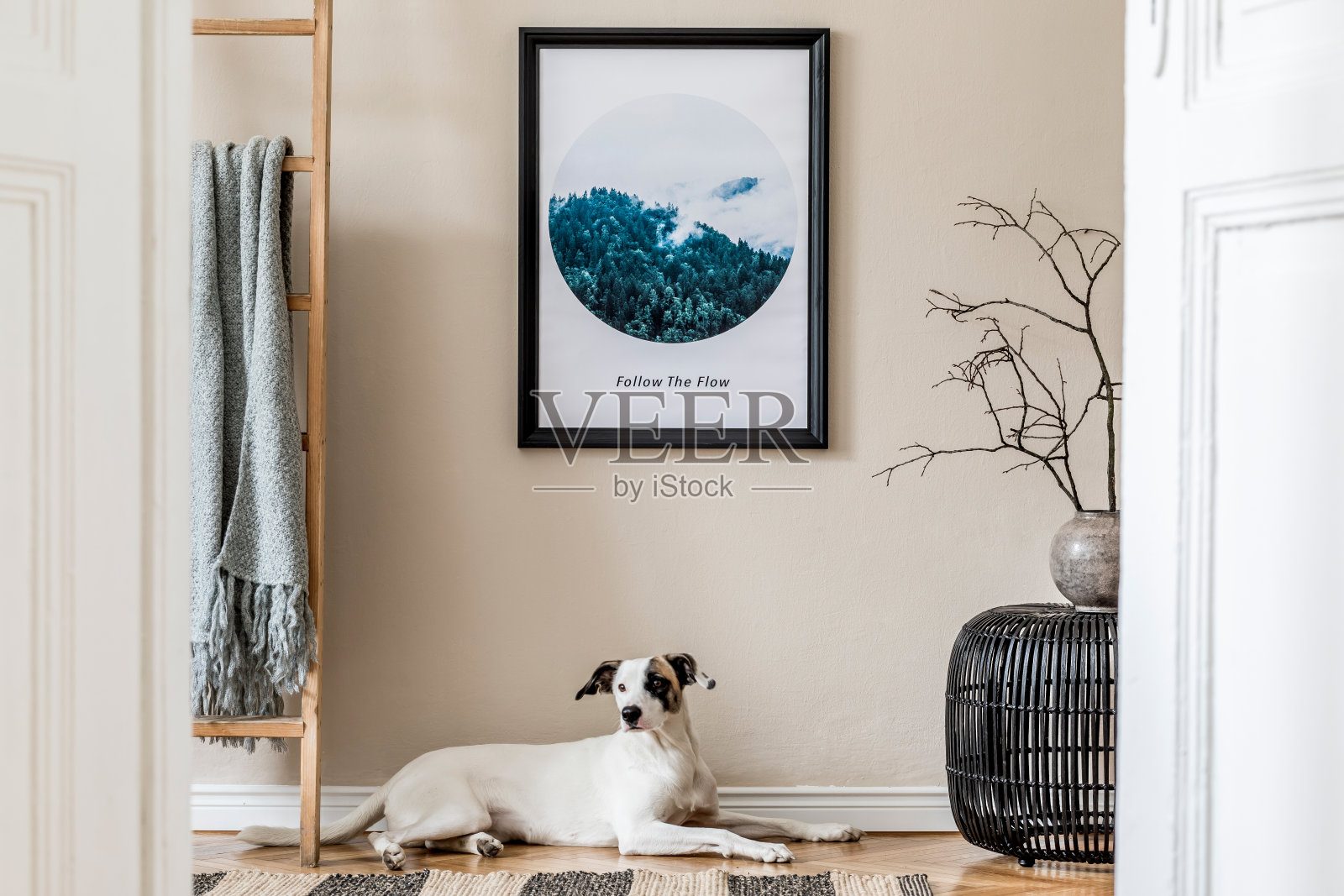 客厅室内设计有黑藤蒲团、花瓶插花、木梯、格子花纹和优雅的配饰。时尚的家里举办。模板。模拟海报框架。狗躺在地板上。照片摄影图片
