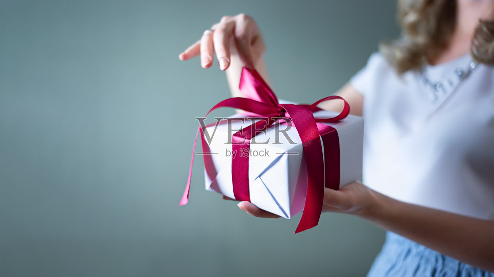 一个女人的手打开一个蓝色背景的礼品盒。情人节，生日概念。照片摄影图片
