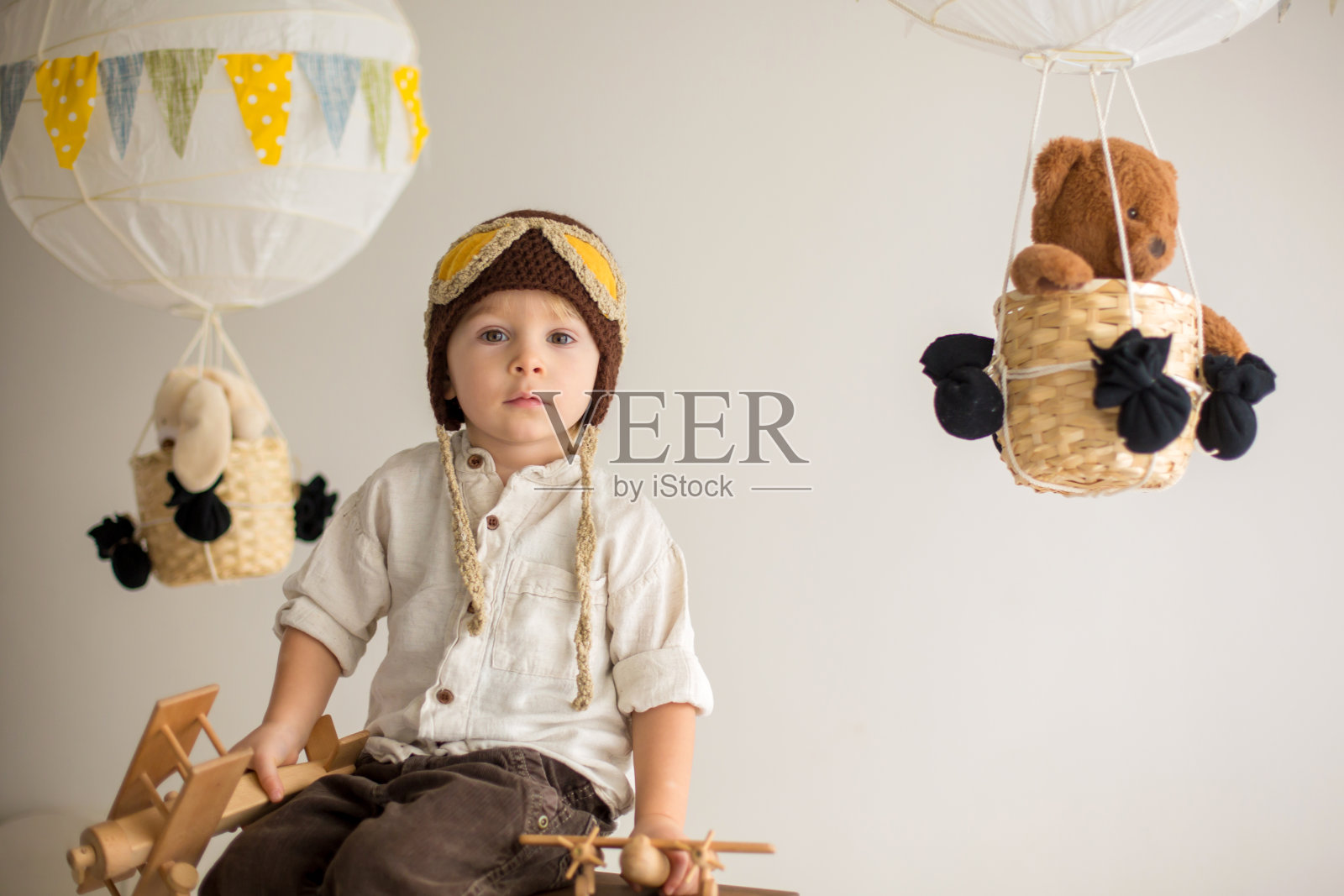 可爱的蹒跚学步的男孩，玩飞机和泰迪熊，气球和身后的玩具照片摄影图片