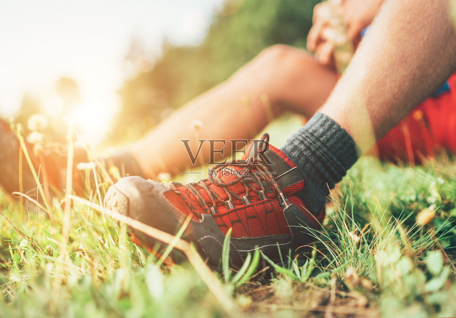 背包客的徒步靴近距离拍摄。人坐在绿草如茵的草地上休息休息，享受登山，积极运动背包健康的生活方式理念照片摄影图片