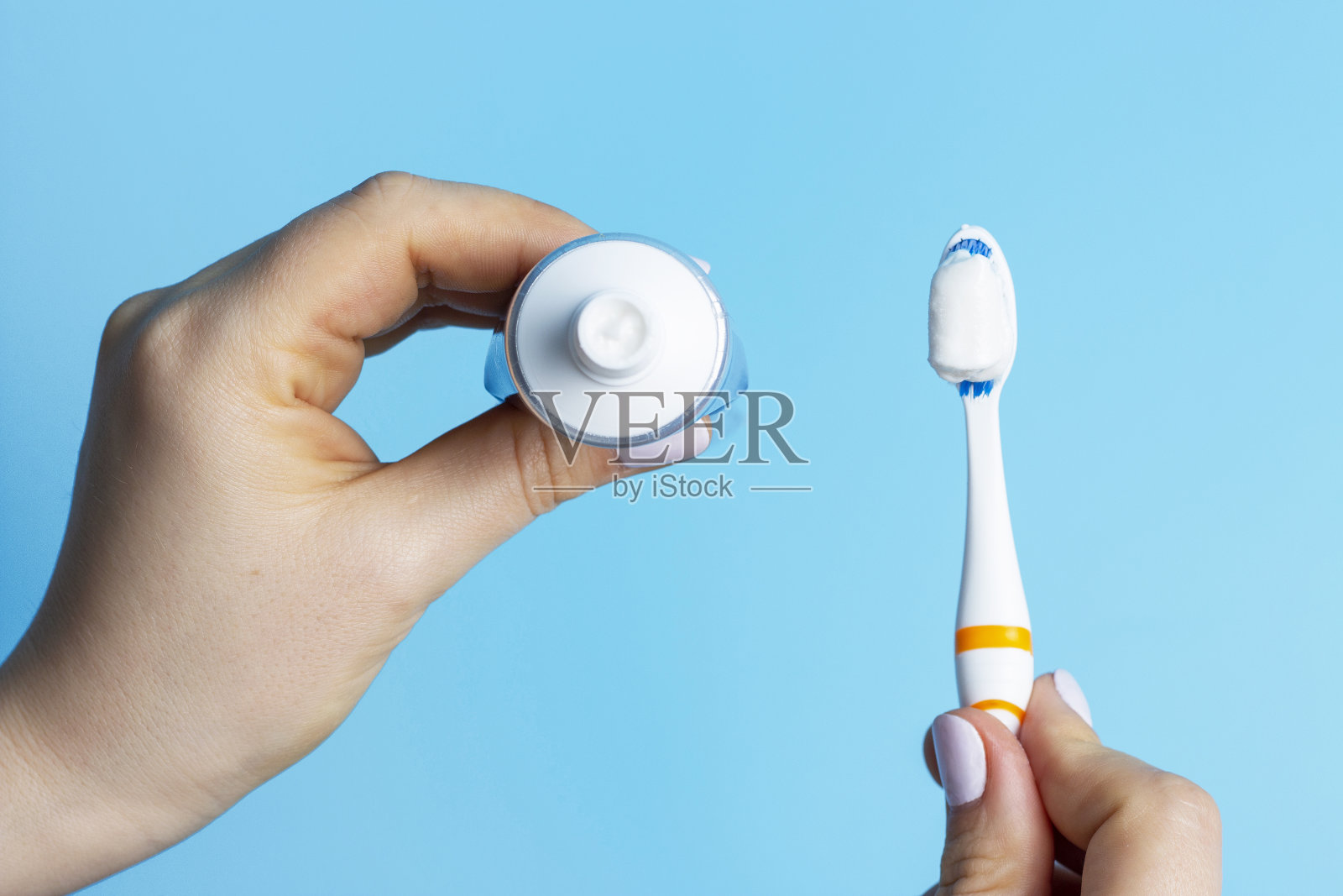 女士双手握住牙刷和牙膏管俯视图。照片摄影图片