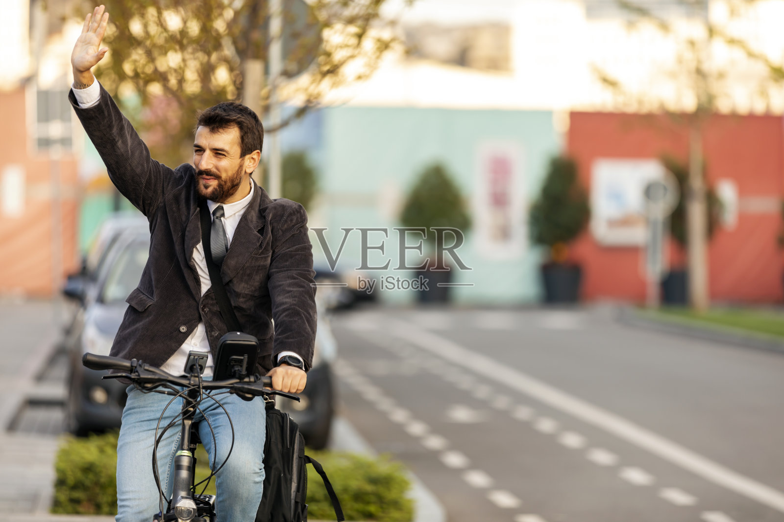 自信的年轻商人与骑自行车在城市街道和挥舞他的手照片摄影图片