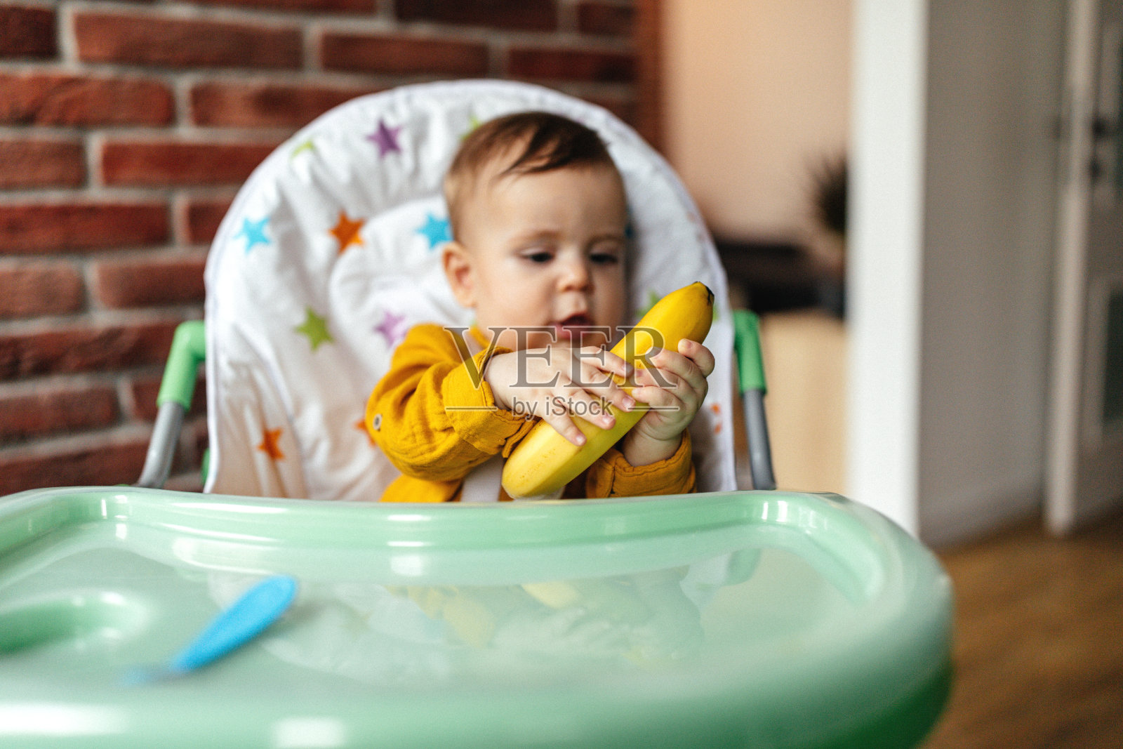 饥饿的婴儿坐在她的椅子上照片摄影图片