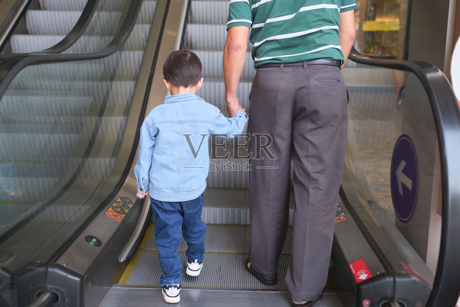 3岁蹒跚学步的亚洲小男孩和爸爸在百货商店拉着自动扶梯，父子俩在购物照片摄影图片