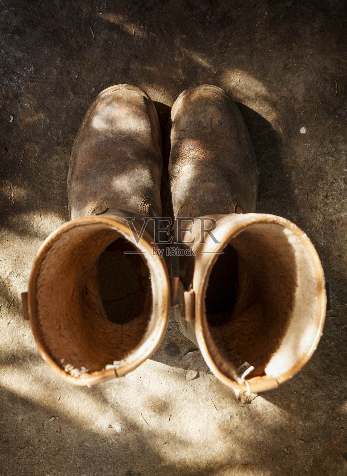 又旧又旧的棕色工作靴，从上面的棚子地板上射下来照片摄影图片