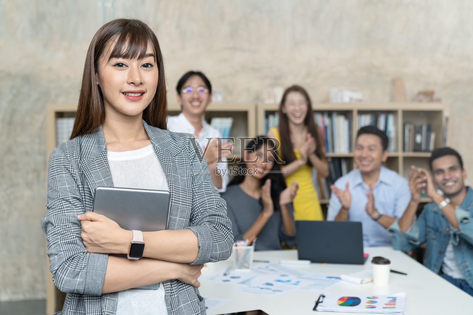 领导亚洲创意女性或领导员工感到高兴和微笑是站在小团体鼓掌在创意办公室的工作场所。女人自信的微笑的脸。照片摄影图片