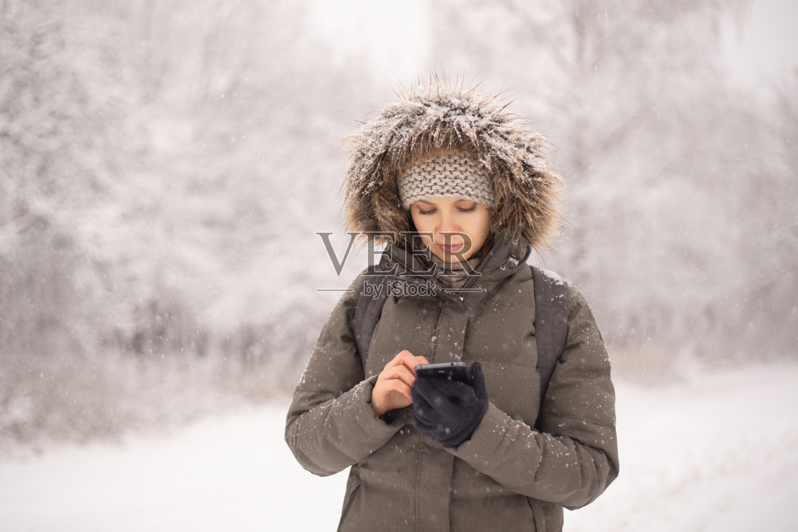 一名女子在下雪的森林里使用智能手机照片摄影图片