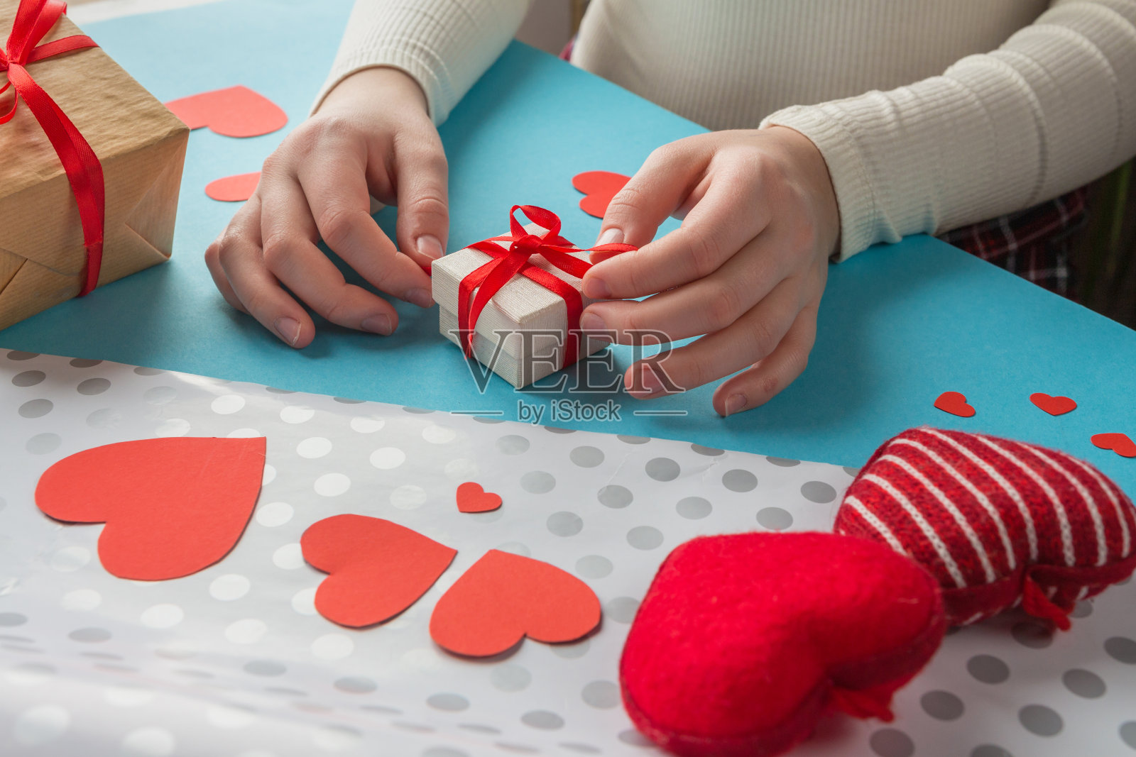 女孩的手为情人节准备了一份礼物，手工制作的情人卡在蓝色的背景上照片摄影图片