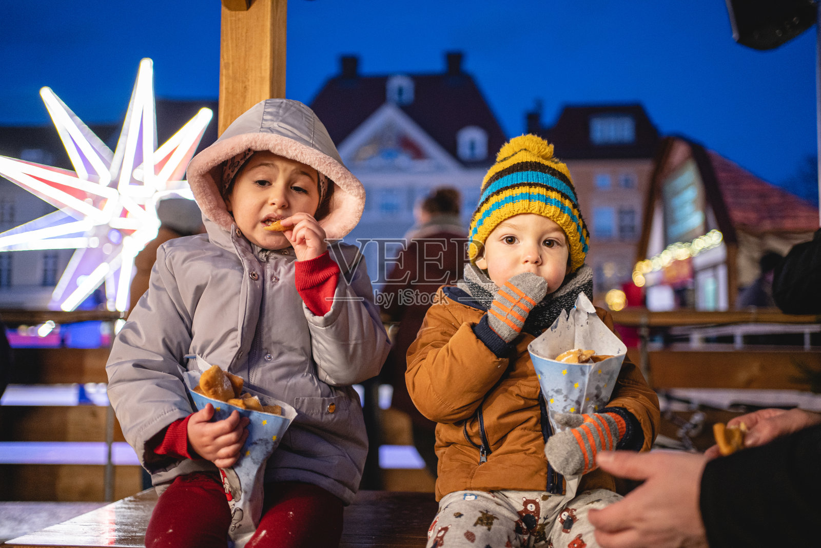 哥哥和妹妹在圣诞市场享受温暖的甜甜圈照片摄影图片
