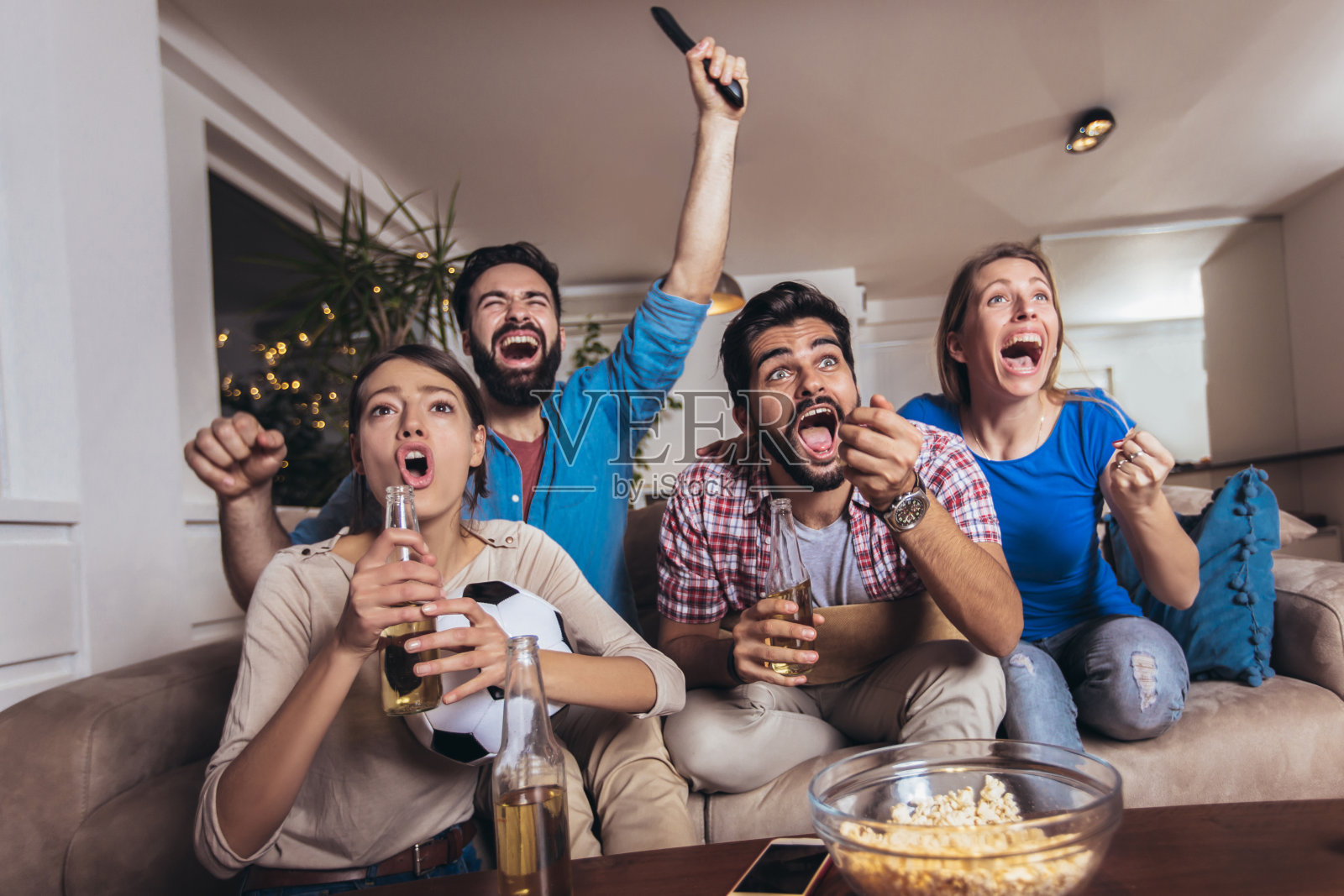 快乐的商业人士或球迷在电视上观看足球比赛并庆祝胜利。友谊、运动、娱乐理念。照片摄影图片
