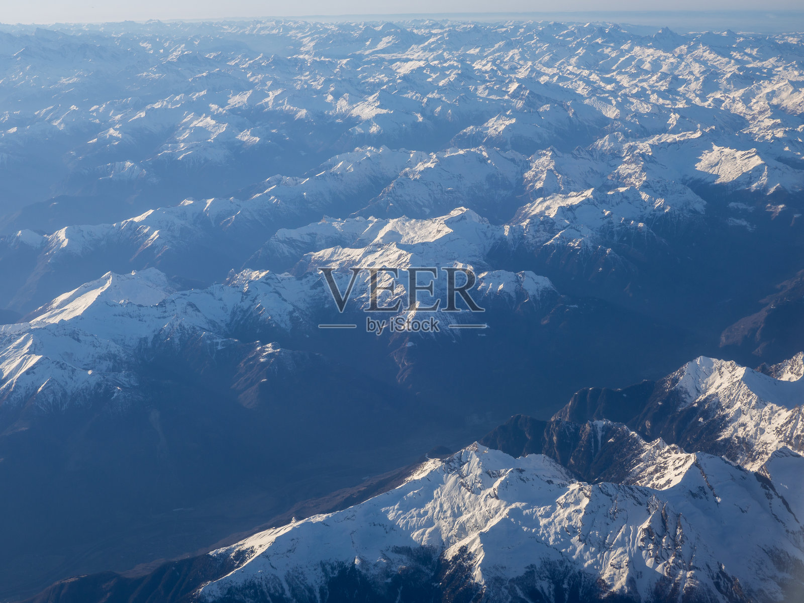 空中风景的阿尔卑斯山在欧洲冬季与新鲜的雪。从飞机窗口可以看到令人惊叹的景色照片摄影图片