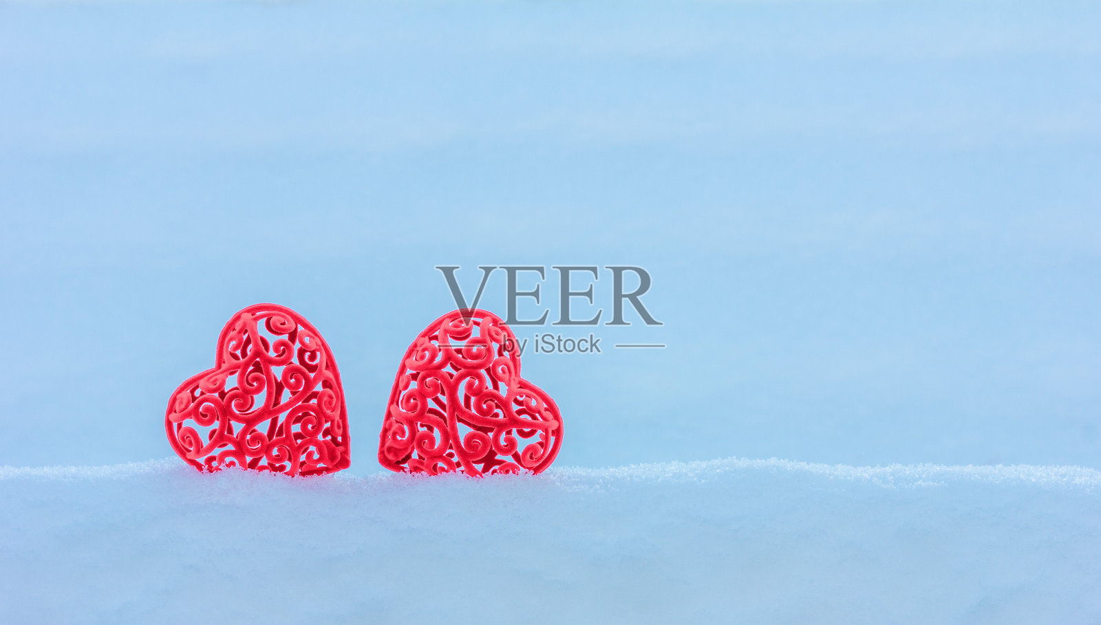 两颗红色的天鹅绒心在雪堆上，在白雪皑皑的背景上复制空间，情人节卡片照片摄影图片