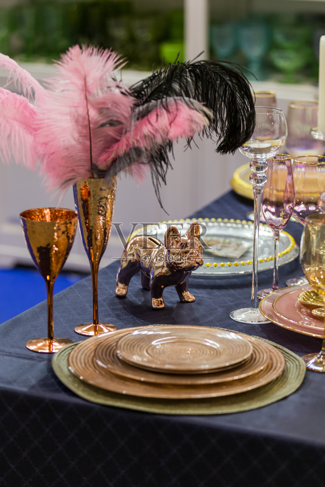 在婚礼或其他场合用金色和粉红色装饰的餐桌，酒杯、盘子、勺子、叉子和蜡烛照片摄影图片