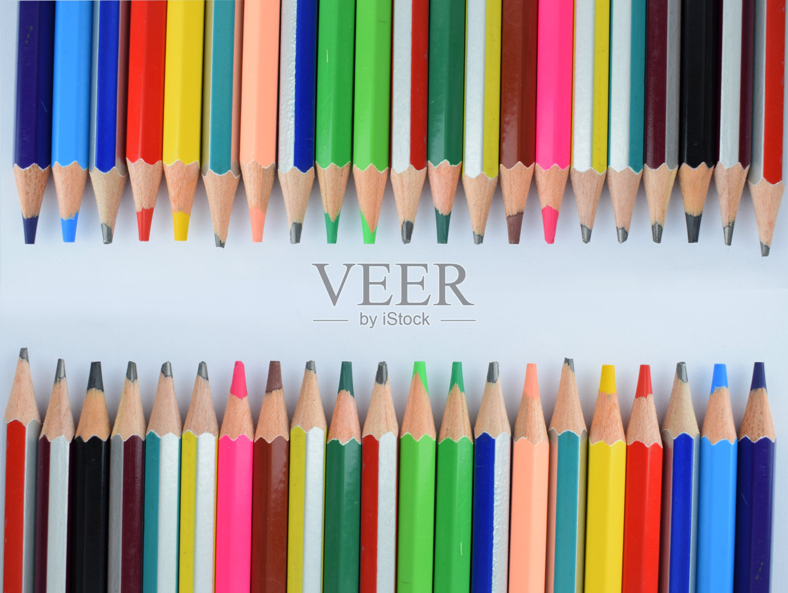 一堆不同颜色的铅笔蜡笔排列成两排，因为它们面对着对方照片摄影图片