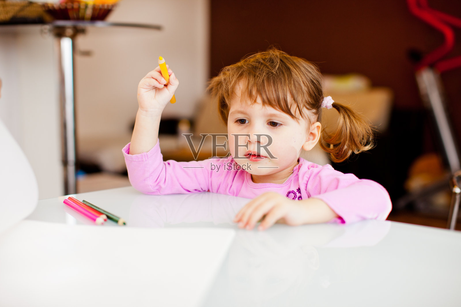 可爱的小女孩坐在桌子上拿着彩色铅笔准备在空白纸上画画-库存照片照片摄影图片