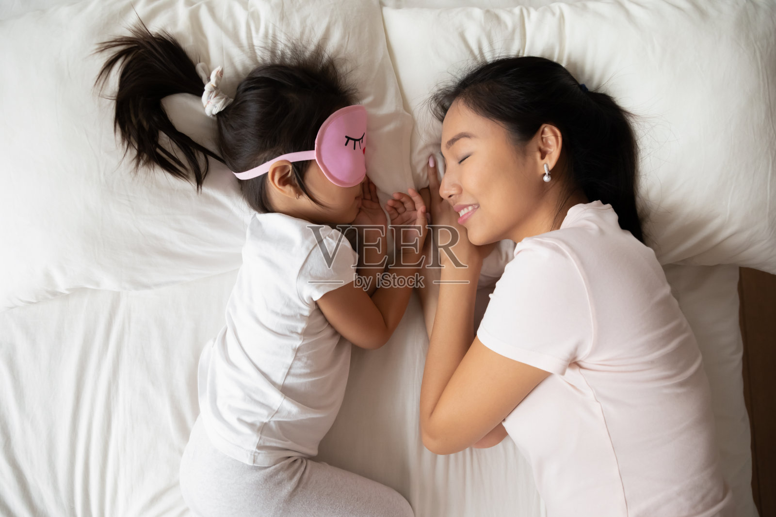 亚洲年轻的妈妈和小女儿睡在舒适的床上照片摄影图片
