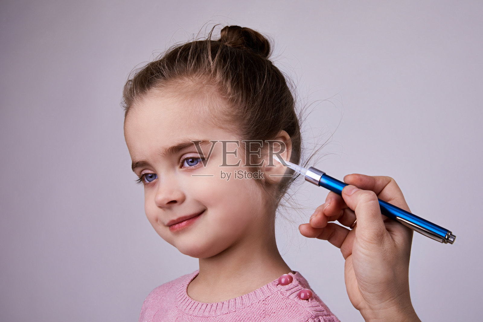医生用医用手电筒笔检查女孩的耳朵。照片摄影图片