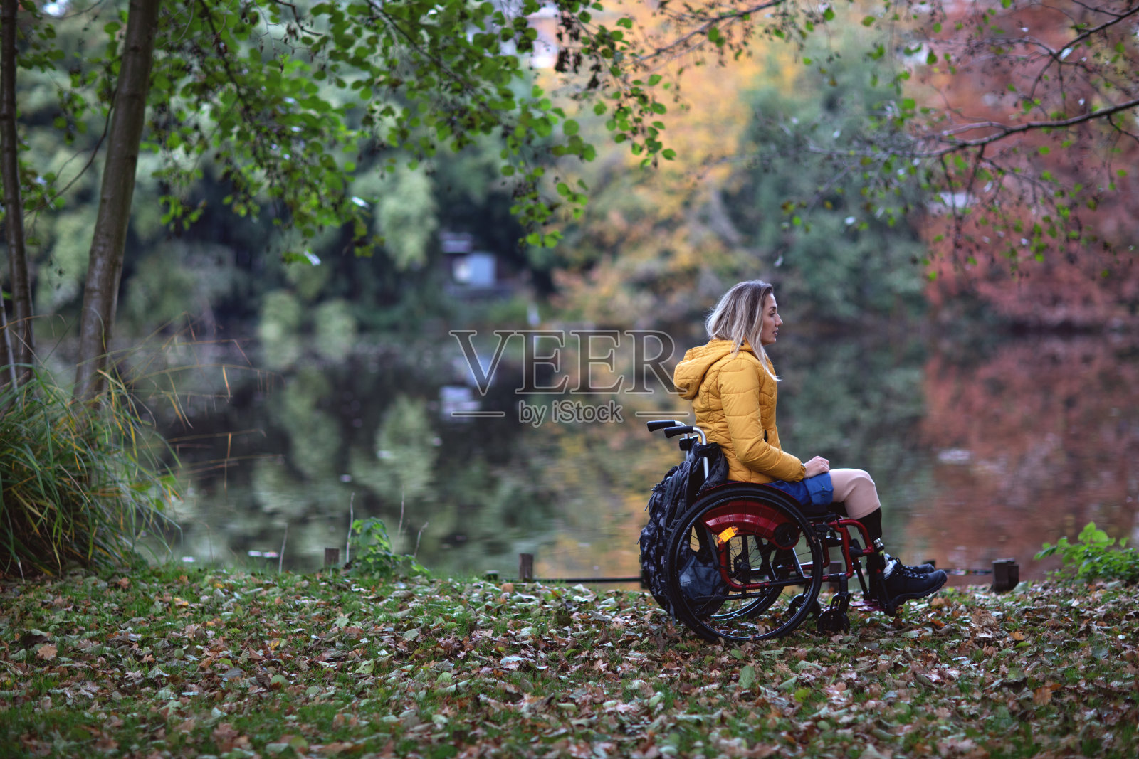 一个没有腿的残疾妇女坐在轮椅上。照片摄影图片