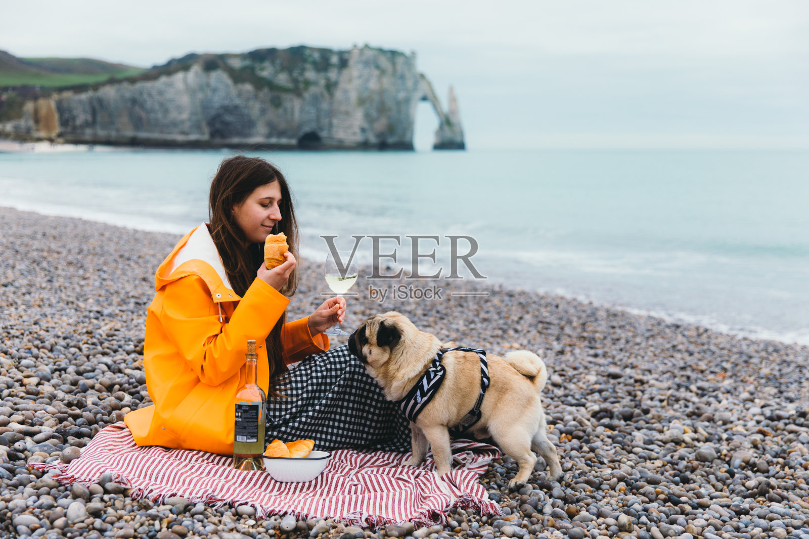 一个女人和一只狗在法国美丽的拱门附近的海滩上进行完美的野餐照片摄影图片