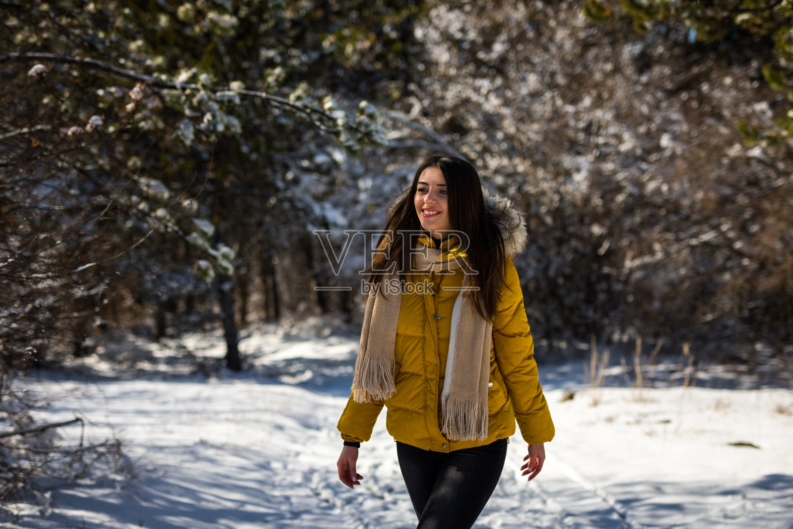 微笑的女人走在森林的雪地上照片摄影图片