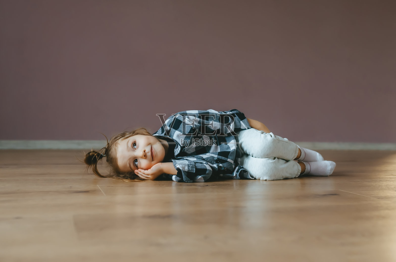 一个可爱的小女孩躺在室内地板上的滑稽肖像照片摄影图片