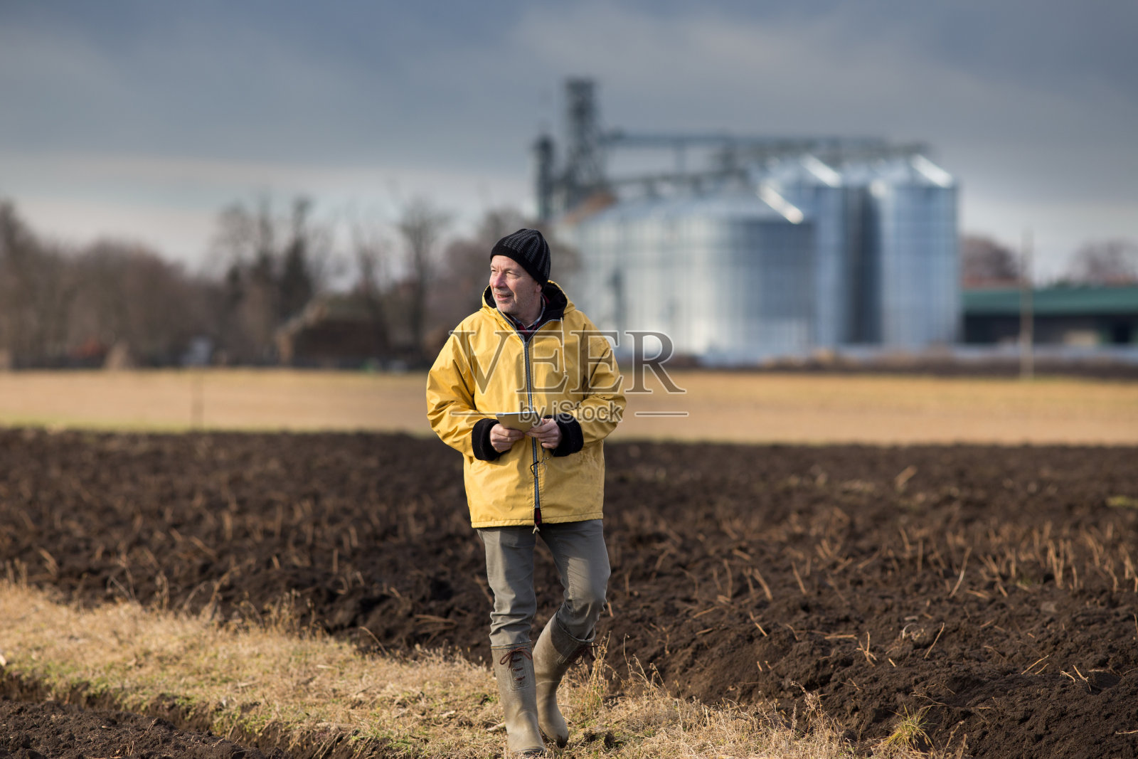 农夫拿着石板站在田间的粮仓前照片摄影图片