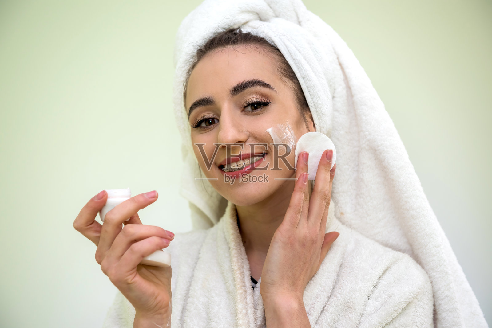 手里拿着面霜在化妆的漂亮女人。皮肤护理清洁。照片摄影图片