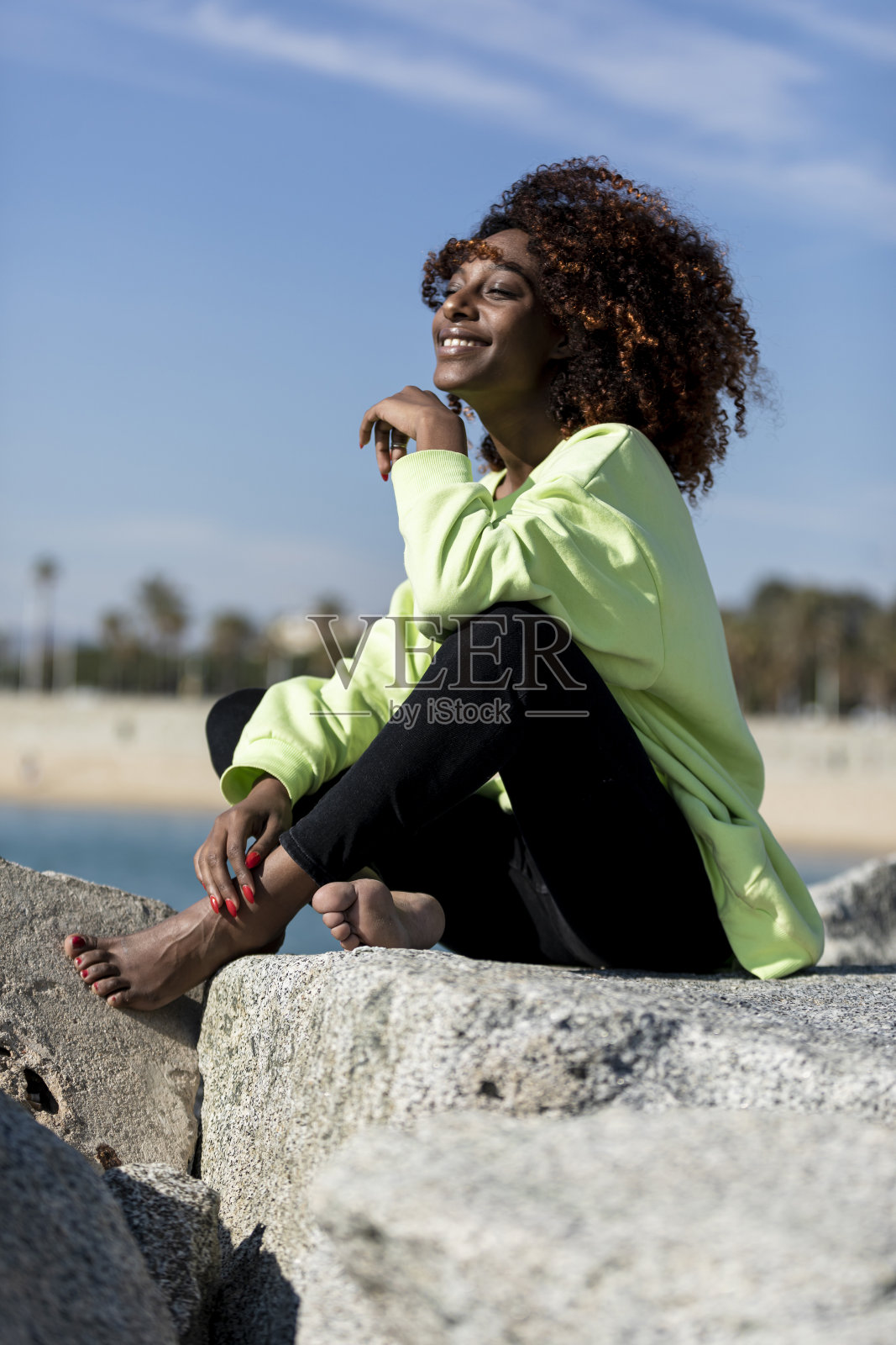 阳光明媚的一天，美丽的美国黑人坐在岸边照片摄影图片