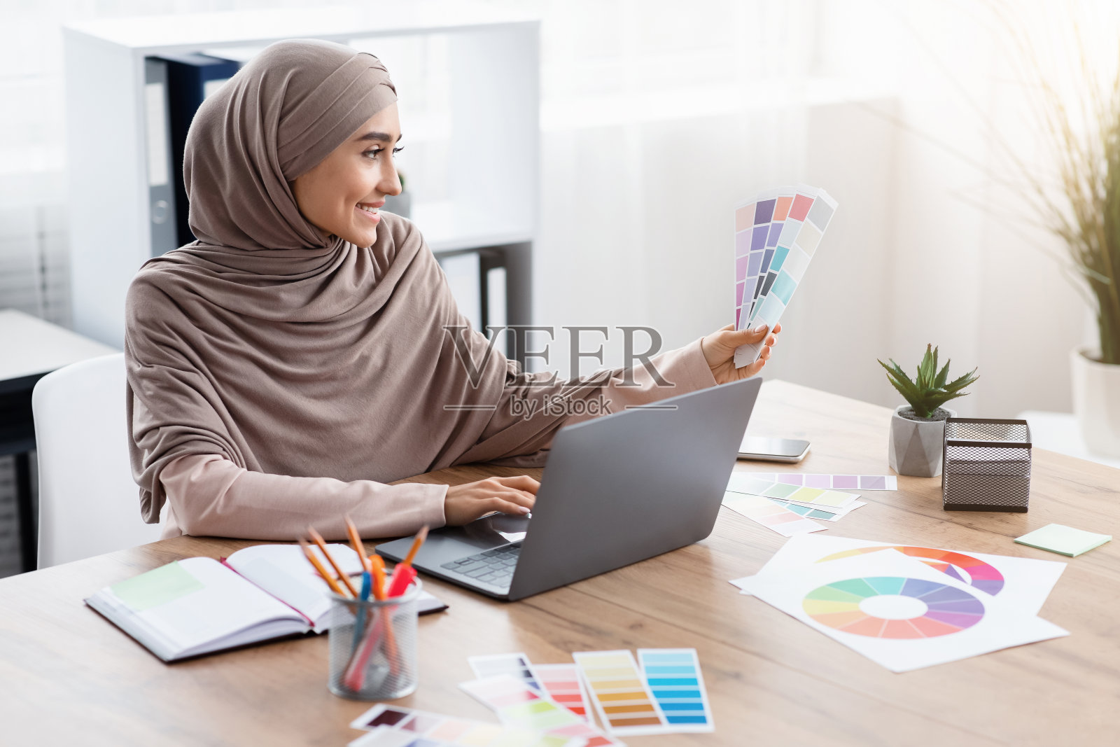 穆斯林女性设计师工作与调色板和笔记本电脑在办公室照片摄影图片