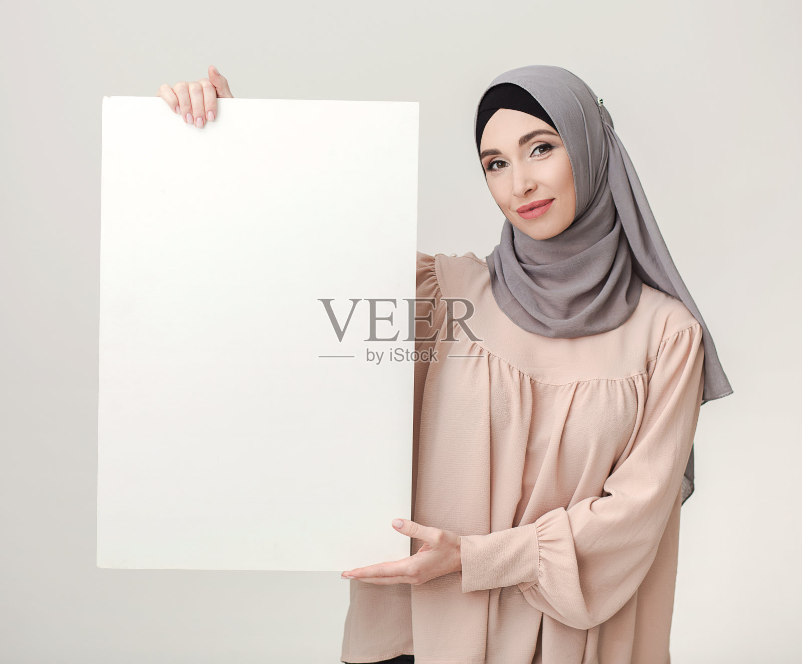 一名妇女戴着头巾，举着斋月贺词的白色海报照片摄影图片