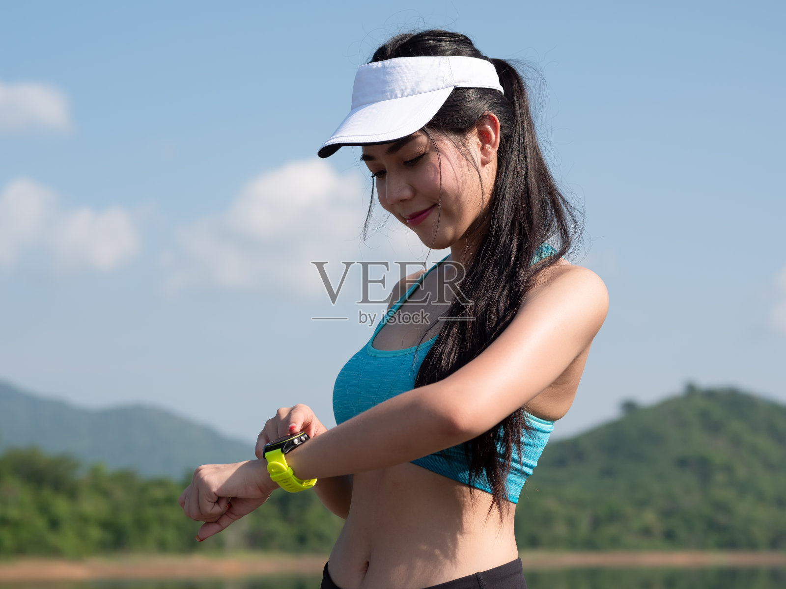 年轻的亚洲女性身材苗条，身材健美，性感的运动服设置健身智能手表在路上跑步。女运动员，健康的生活方式概念。照片摄影图片