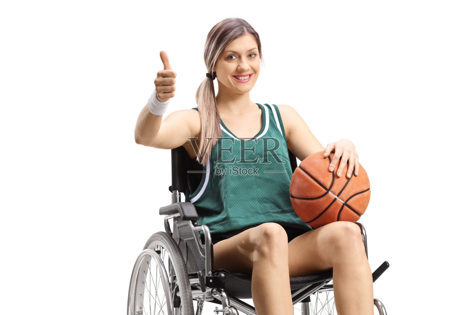 坐在轮椅上的年轻女子拿着篮球，竖起大拇指照片摄影图片