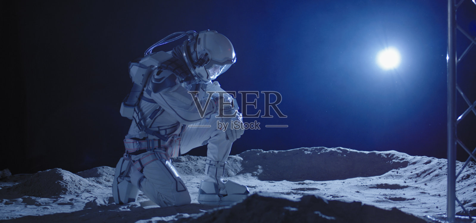 宇航员跪在月球上照片摄影图片