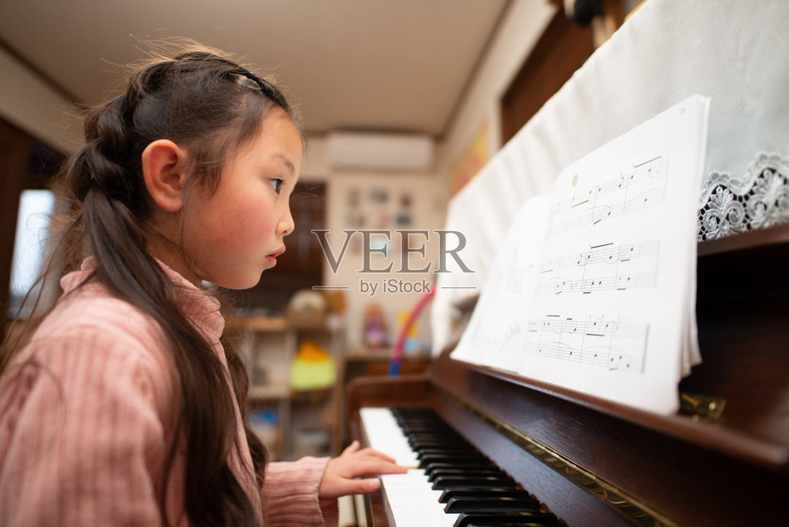 女孩通过看乐谱来练习钢琴照片摄影图片