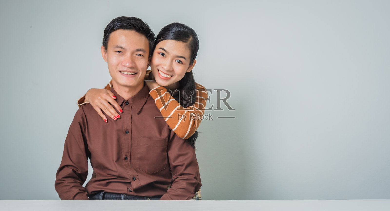 年轻幸福的亚洲情侣情侣在棕色衬衫漂亮的女人和瘦男人。照片摄影图片