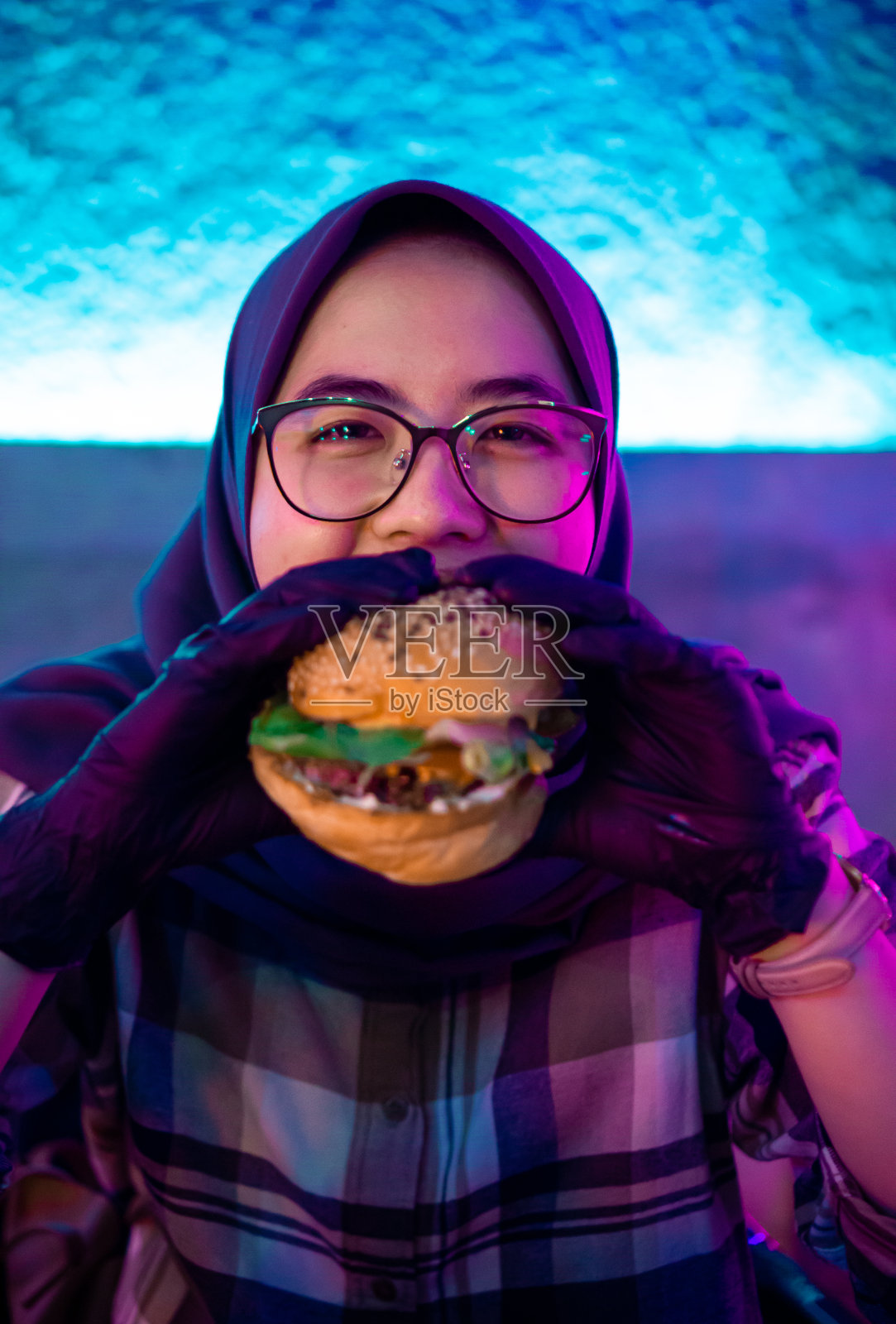 亚洲千禧女孩兴奋地吃着五颜六色的汉堡照片摄影图片