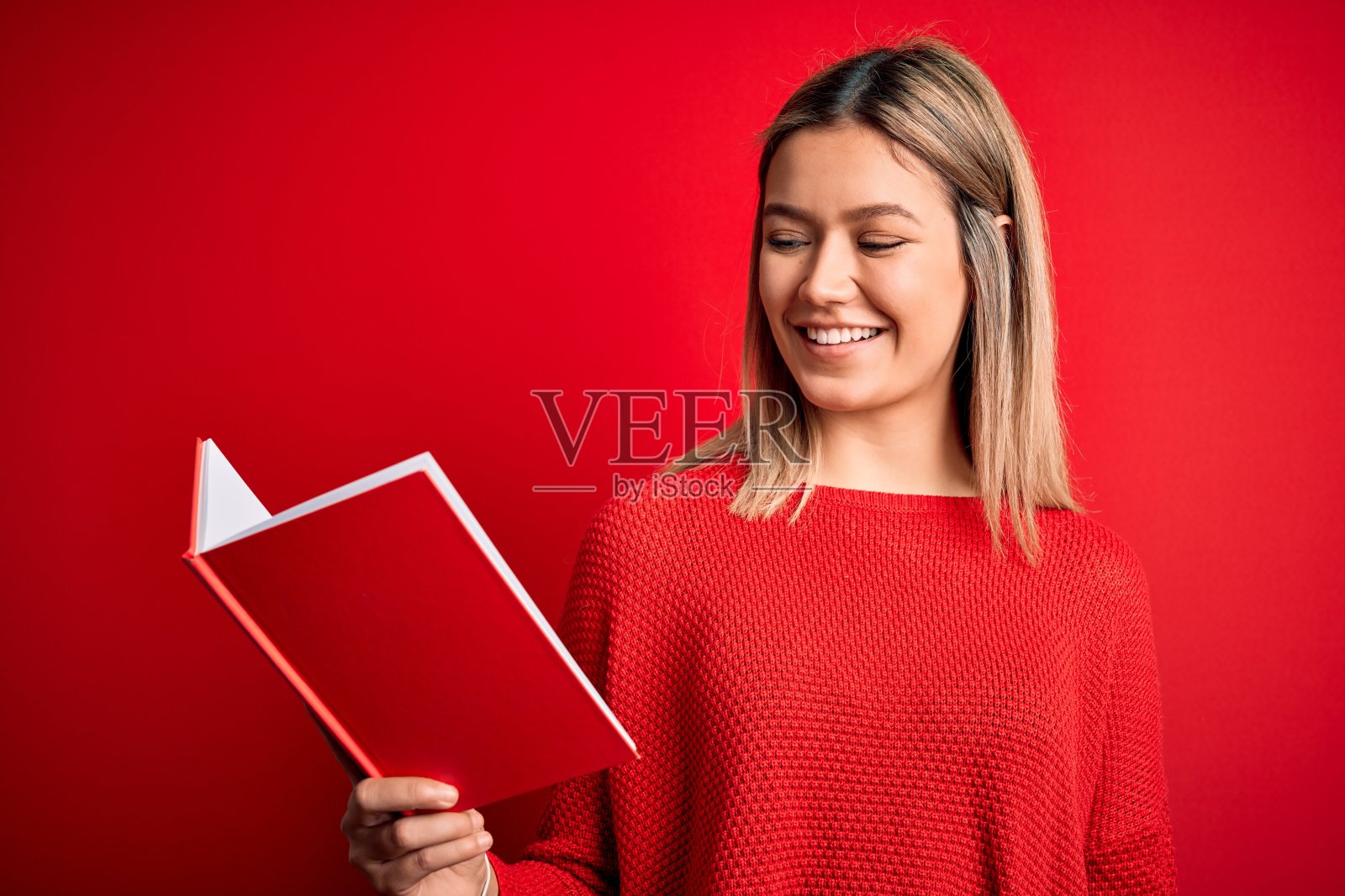 年轻美丽的女人读书站在孤立的红色背景与快乐的脸站和微笑与自信的微笑显示牙齿照片摄影图片