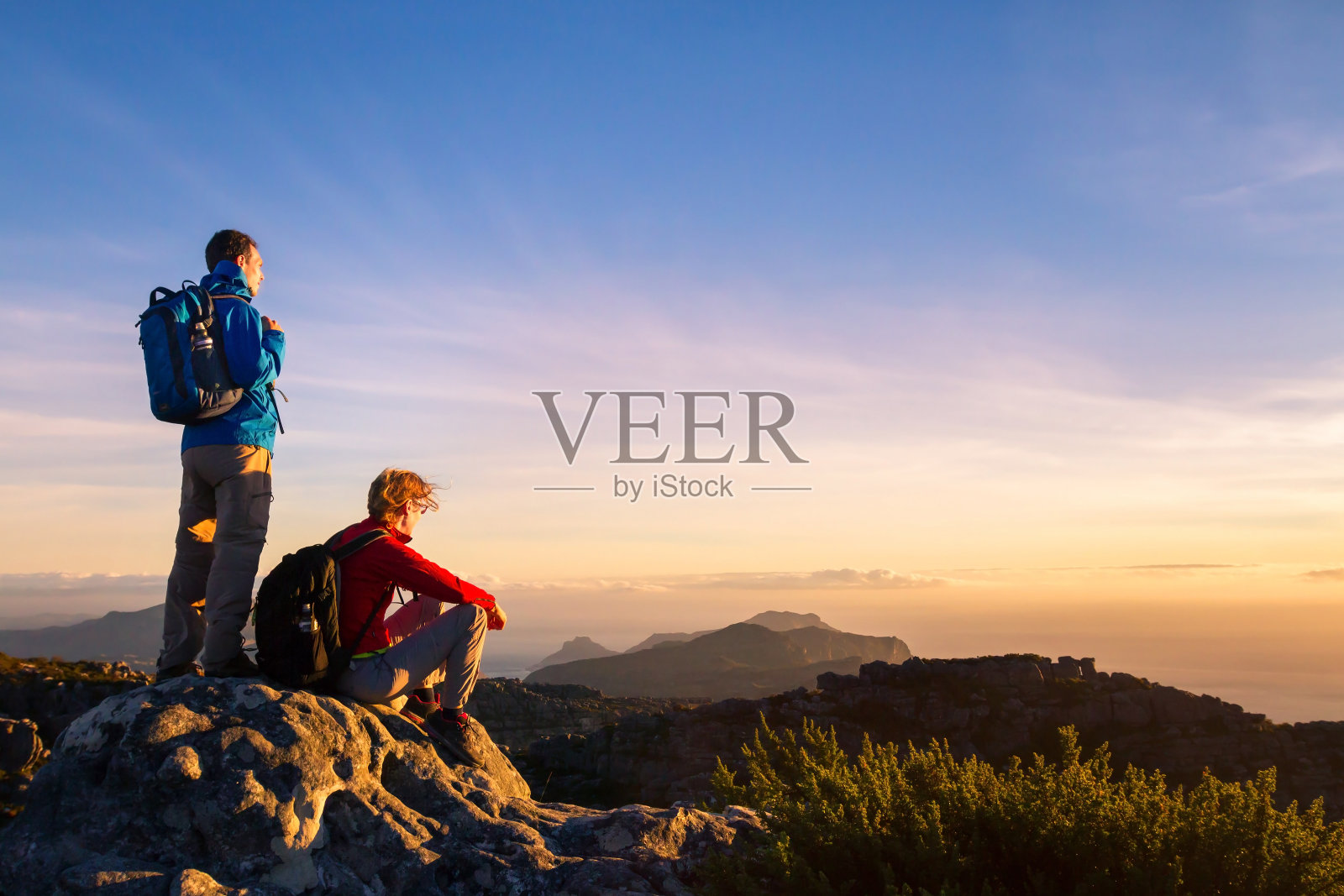 一对背包徒步者在山中享受日落全景，旅行照片摄影图片