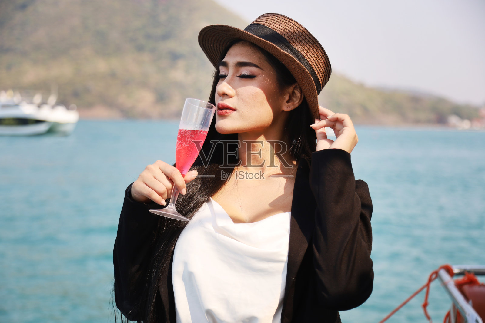 美丽的亚洲女人微笑肖像旅游和喝葡萄酒在快艇在夏天放松在泰国。照片摄影图片