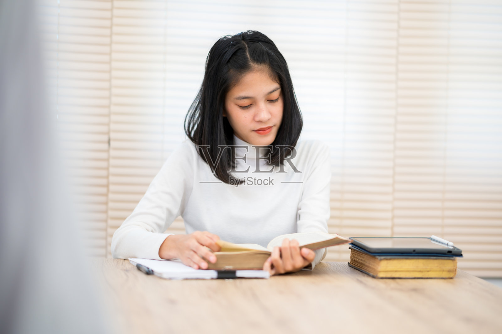 一位穿着白衬衫的亚洲女学生坐在大学里读书照片摄影图片