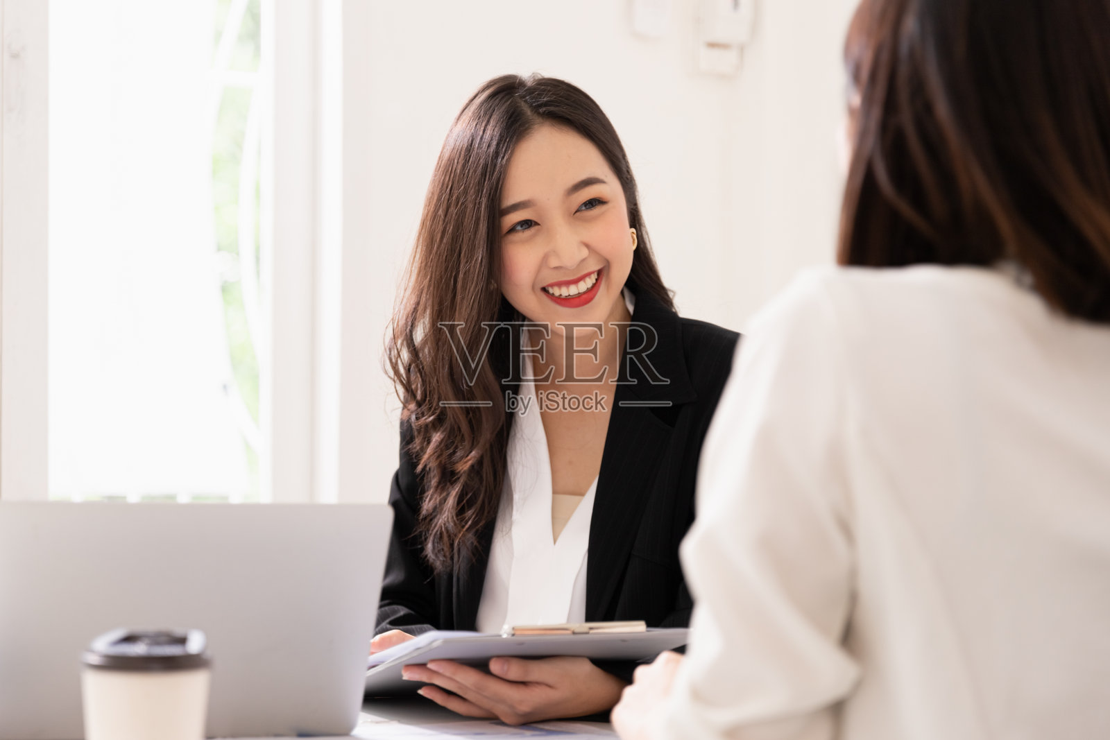 一个年轻迷人的亚洲女人正在面试一份工作。她的面试官形形色色。人力资源经理在办公室与求职者进行面试照片摄影图片
