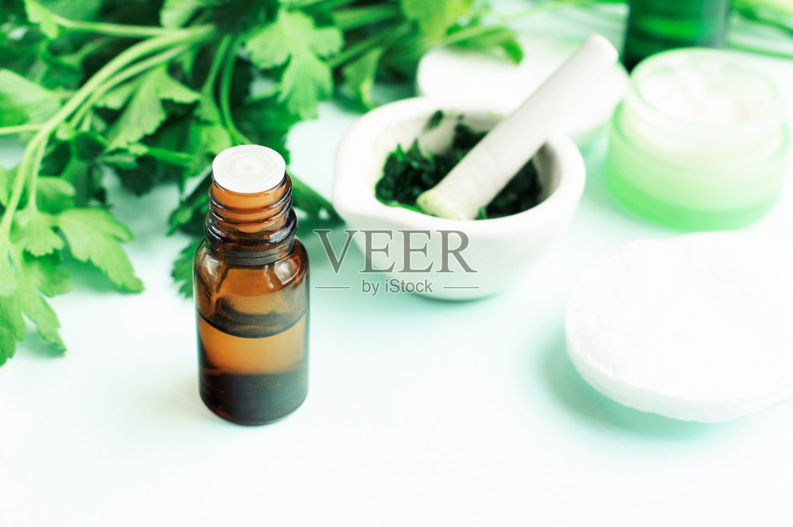 植物疗法:欧芹萃取的草药护肤，新鲜的绿色植物配香水瓶照片摄影图片