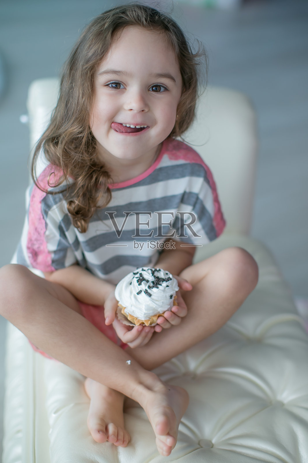 可爱的女孩坐在白色柔软的沙发上，吃着一个明亮的节日蛋糕照片摄影图片
