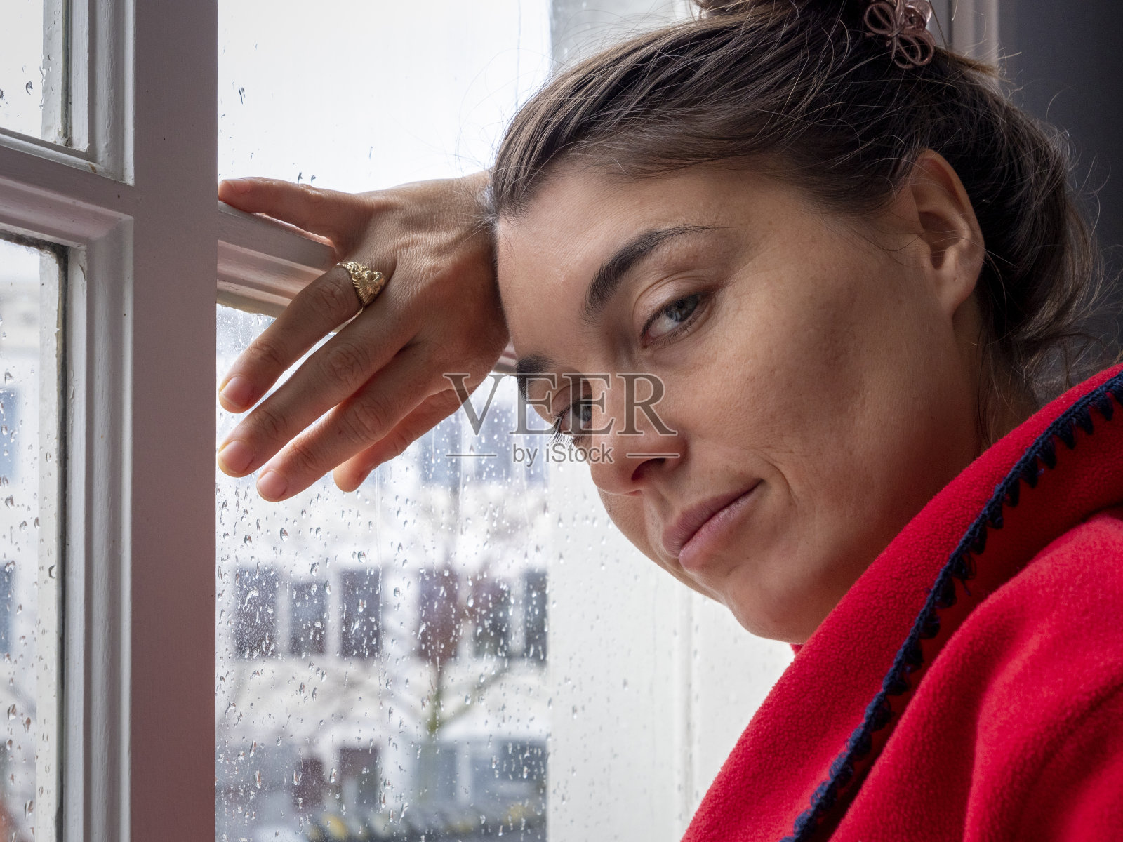 一个沉思的女人看着相机，在雨天的窗口照片摄影图片