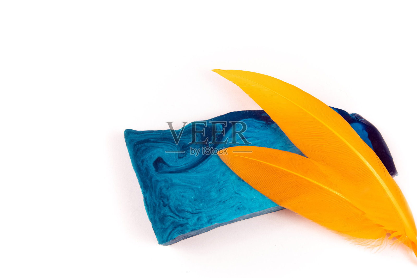 一块薄而平的蓝色薄荷手工肥皂和两个橙色的羽毛照片摄影图片