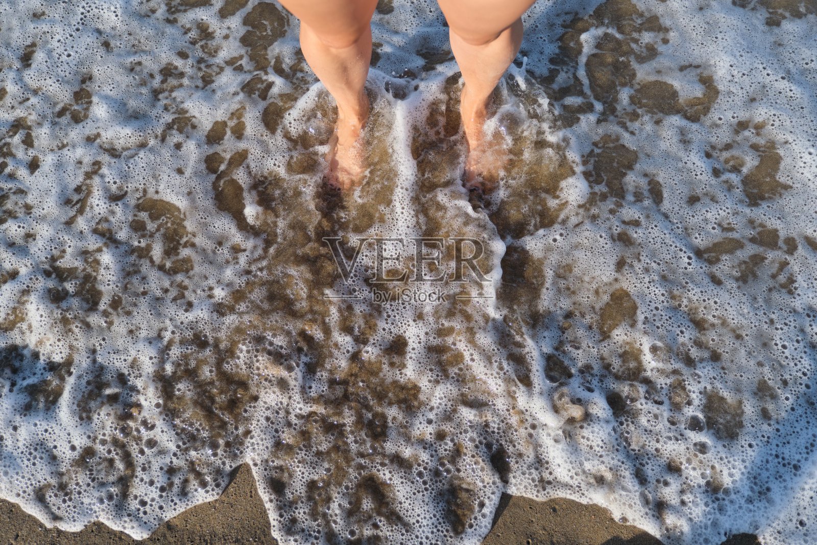 海泡沫波洗女人光脚，俯视图照片摄影图片